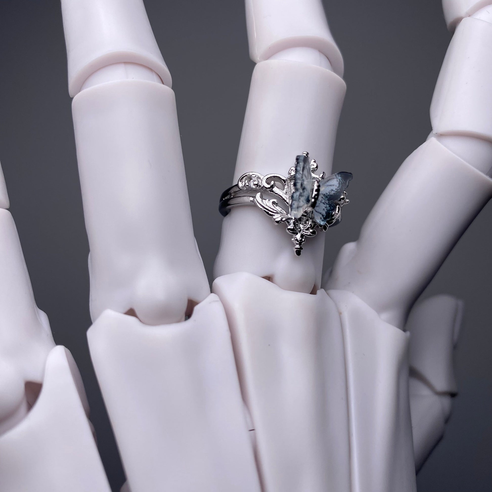 Silver ring with a large gemstone on a white hand model against a dark background