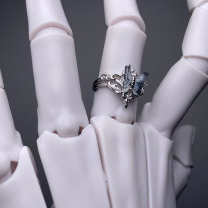 Silver ring with a large gemstone on a white hand model against a dark background